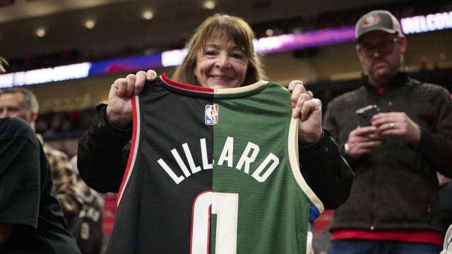 A basketball fan holds a jersey with the colors and number of the Portland Trail Blazers and Milwaukee Bucks guard Damian Lillard (0) a